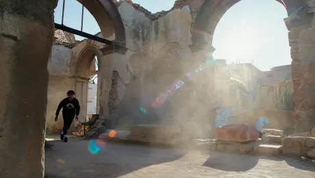 Dust motes dance in the sunbeams slicing through crumbling archways as a Parkour athlete, a figure of fluid motion against the decaying grandeur, flows seamlessly across the ruins;  the textured surfaces—rough stone, crumbling plaster, and rusted metal—provide a stark yet beautiful backdrop to their breathtaking leaps and climbs, each movement a testament to both human strength and the relentless march of time.