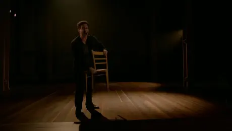 The actor in the image shouts passionately and throws a chair across the stage, dramatic lighting, camera pushes forward and tilts for intensity