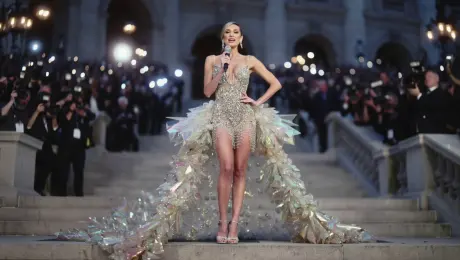 An iconic pop superstar poses dramatically on the steps of a grand gala, surrounded by the blinding flashes of paparazzi cameras. She wears an avant-garde gown made of iridescent, crystalline structures that seem to defy gravity. She holds a tiny, jewel-encrusted microphone. With a confident smirk, she tells a reporter: “This year’s theme? Auditory Couture. My gown is literally singing, and the texture of the sound is all Wan2.5 from WaveSpeedAI. It’s the only accessory I need.” Stroboscopic flashbulb effect, glamorous soft lighting, bokeh background of lights and crowds, low-angle full-body shot, Vogue editorial style.
