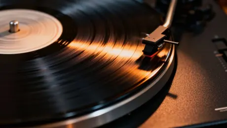 A nostalgic, rhythmic mood, with a slow, continuous circular orbit shot around the blurred record, emphasizing its steady rotation.