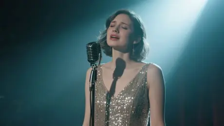 a female singer in a sparkling silver gown performs under a soft spotlight on a moody, dimly lit stage. She holds a vintage microphone and sings with deep emotion, her lips perfectly synced with the vocals:“I keep on dreaming under neon skies, hoping love will find me one more time.”The audio features her soulful voice singing these lines. The camera gently pans from a close-up of her face to a wide shot of the stage, highlighting the shimmer of her dress and the atmosphere of the performance.