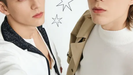 Please merge the two figures in the image into a single double-person overhead selfie composite. Preserve the facial features, clothing details, and accessories of both subjects from Image 1 and Image 2, maintaining a portrait-style photographic composition. Both figures should look directly at the camera, creating a strong visual impact: one person should appear to be holding the frame, creating the illusion of a “selfie perspective.” The male figure on the left must remain unchanged—no face swapping. The male figure on the right must retain its original features—no face swapping. The shooting angle should be a high overhead view, consistent with the typical Korean/Japanese selfie aesthetic. The background is pure white, clean and minimalist, further highlighting the subjects. The final result achieves a refined, fashionable portrait effect. The subjects must blend seamlessly into the frame with natural visual transitions, and the overall lighting must be bright and even! The full-body shot features natural, textured lighting with star doodle elements in the background, conveying a subcultural aesthetic.