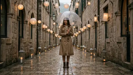 The woman walks down the lantern-lit alley, rain tapping gently on her umbrella as she approaches the café entrance. She steps inside, closing the umbrella beside her, and walks to the counter. After receiving the cup, she carries it to a window seat, sits down, and wraps her hands around the warm drink while watching the rain outside.