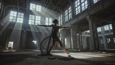 A professional contemporary dancer performing fluid, expressive movements and leaps through a cavernous, industrial abandoned warehouse. As they spin, dust particles swirl around their limbs and the minimalist fabric of their attire trails behind in slow motion. The camera executes a dynamic 360-degree orbital tracking shot, circling the performer from a low angle to emphasize height and grace. High-contrast volumetric "God rays" pierce through shattered high-altitude windows, illuminating the hazy atmosphere and airborne dust motes. Cinematic 4K, shallow depth of field with sharp focus on the dancer’s expressions, gritty industrial textures, and high dynamic range.