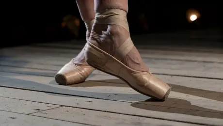 An extremely frail elderly ballerina, 80s, in a tattered tutu, performs alone on an abandoned theater stage lit only by a single spotlight.
Shot 1: Close-up on her gnarled, arthritic feet slowly sliding into first position on the dusty stage floor, the sound of creaking wood beneath her.
Shot 2: Wide shot — she raises her arms overhead with trembling elegance, spine straightening inch by inch, the empty velvet seats stretching into darkness behind her.
Shot 3: Medium shot — she begins to turn, slowly at first, then faster, her tutu catching the light, dust swirling around her ankles like smoke.
Shot 4: Low-angle shot — she launches into a grand jeté, body suspended impossibly in the air for a breathless moment, face locked in pure, fierce concentration.
Shot 5: She lands, staggers one step, then stands perfectly still — chest heaving, tears streaming silently — and takes a deep, solitary bow to no one.
The mood is bittersweet and haunting, soaked in faded glory and unbroken love for a life lived in motion.