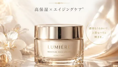 Generates a high-end cosmetic product advertisement with elegant typography, a glowing background, and a call-to-action button.
A luxurious cosmetic product advertisement featuring a single elegant glass jar with a shiny gold lid resting on a round, light-colored marble slab. The jar has gold text reading {argument name="brand name" default="LUMIÉRE"} and {argument name="product type" default="MOISTURE RICH CREAM"} with "AGING CARE*" below it. The background consists of soft, draped, shimmering champagne-colored silk fabric with delicate white flowers on the left. The lighting is warm, ethereal, and sun-drenched with soft bokeh. At the top center, elegant dark brown Japanese typography reads {argument name="main headline" default="肌に、静かな贅沢を。"} above a small decorative gold divider and the text {argument name="subheadline" default="高保湿×エイジングケア*"}. To the right of the jar, a thin gold circle contains Japanese text meaning 'With dense moisture, high-quality firmness and radiance'. At the bottom center is a dark rectangular call-to-action button with a thin gold border containing the text {argument name="button text" default="詳しく見る"} and a right-pointing chevron. In the bottom right corner, tiny fine print contains Japanese text meaning '*Care according to age'.
