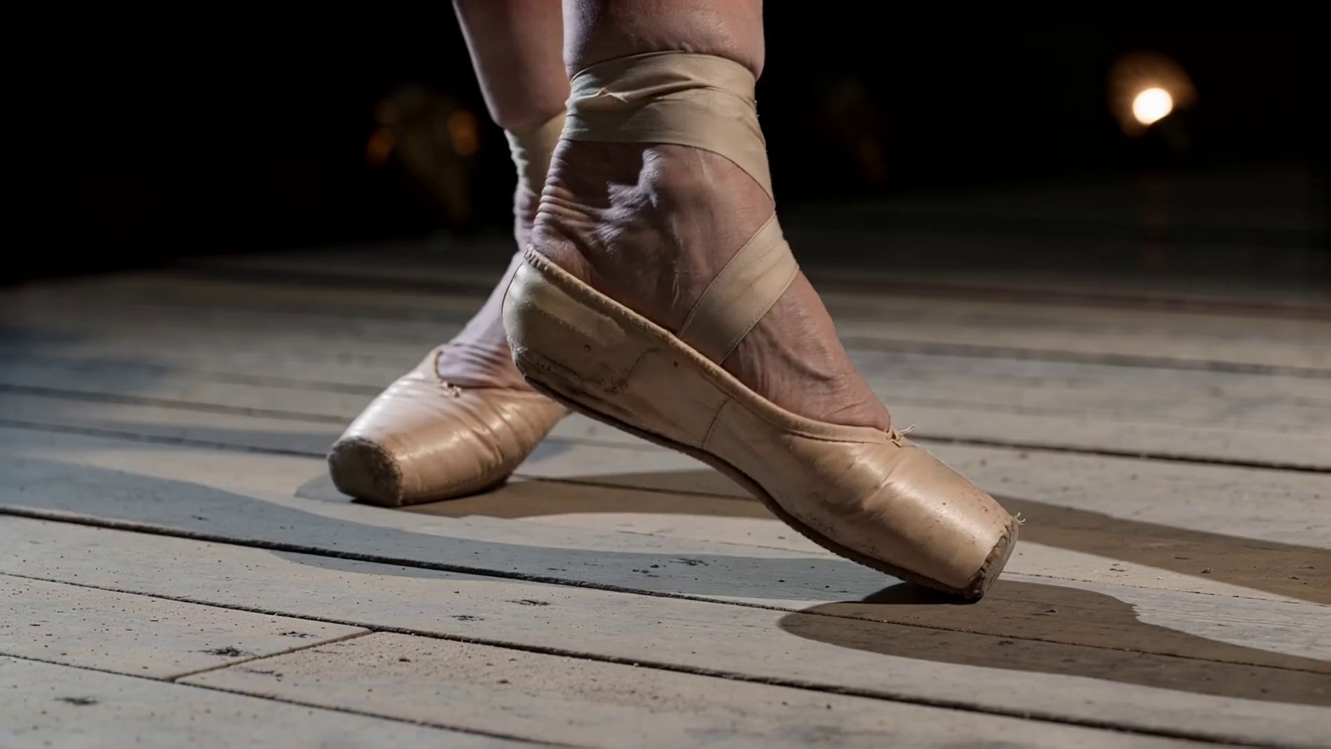 An extremely frail elderly ballerina, 80s, in a tattered tutu, performs alone on an abandoned theater stage lit only by a single spotlight.
Shot 1: Close-up on her gnarled, arthritic feet slowly sliding into first position on the dusty stage floor, the sound of creaking wood beneath her.
Shot 2: Wide shot — she raises her arms overhead with trembling elegance, spine straightening inch by inch, the empty velvet seats stretching into darkness behind her.
Shot 3: Medium shot — she begins to turn, slowly at first, then faster, her tutu catching the light, dust swirling around her ankles like smoke.
Shot 4: Low-angle shot — she launches into a grand jeté, body suspended impossibly in the air for a breathless moment, face locked in pure, fierce concentration.
Shot 5: She lands, staggers one step, then stands perfectly still — chest heaving, tears streaming silently — and takes a deep, solitary bow to no one.
The mood is bittersweet and haunting, soaked in faded glory and unbroken love for a life lived in motion.