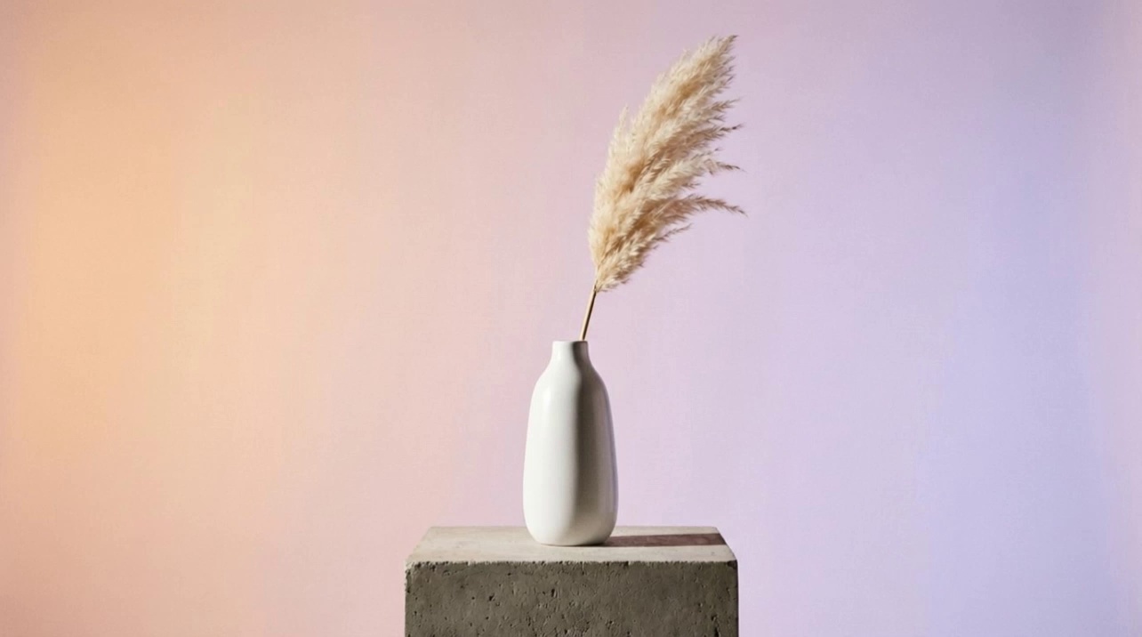 Camera slowly orbits around the vase. Soft light shifts across the ceramic surface. The pampas grass sways gently. Shadows move elegantly. Smooth continuous motion, premium feel.