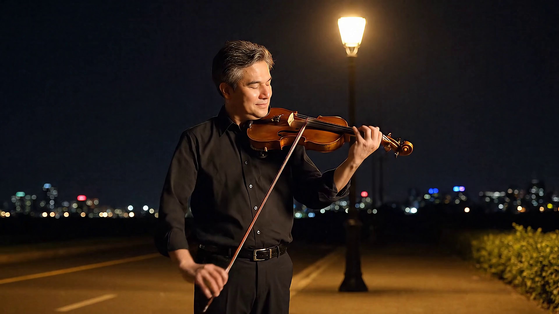 A gentle man is playing the violin by the roadside on a quiet night.