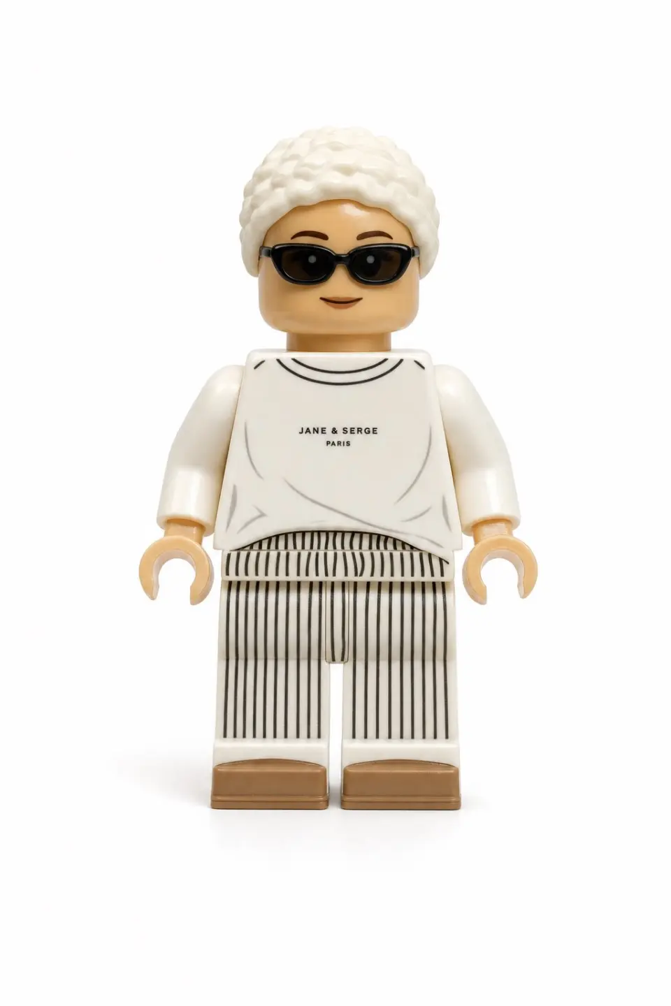 Use the user uploaded image as the only subject reference. Transform the person in the uploaded image into a realistic LEGO style minifigure while preserving their recognizable identity and outfit. Preserve the subject's facial likeness as much as possible within LEGO minifigure design limits, maintaining the same hairstyle and hair color adapted into a LEGO hairpiece, facial expression, clothing colors, clothing design and patterns, and any visible accessories. The result should clearly represent the same person translated into LEGO form. The character must follow authentic LEGO minifigure proportions, including a cylindrical yellow or skin tone LEGO style head, simple printed facial features adapted from the subject, a block shaped torso with printed clothing details, standard LEGO minifigure arms with curved hands, short LEGO minifigure legs, and a distinct molded plastic hairpiece matching the subject's hairstyle.
Render the figure using realistic LEGO plastic material with a slight glossy sheen, subtle molded seams, and natural toy surface reflections. The face and torso should include printed details typical of LEGO minifigures, and the hairpiece should appear as molded plastic. The final image should be a high quality realistic 3D toy render with soft diffused studio lighting, subtle shadows that emphasize shape and plastic texture, and clean sharp focus with crisp detail. The framing must show the full body minifigure from head to feet in a centered composition with the entire figure fully visible. Use a plain white background with no scenery, no props, and no additional elements. The final style should feel like a photorealistic LEGO minifigure toy render with highly detailed plastic texture and studio lighting.